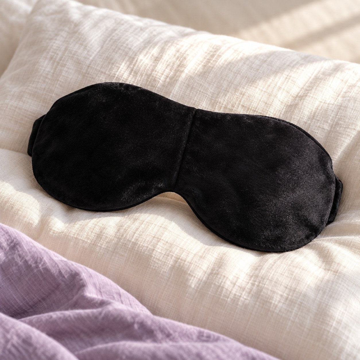 Black weighted sleep mask on soft bedding