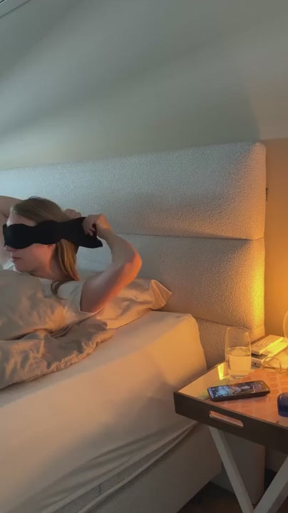Een zwart oogmasker wordt opgezet in bed